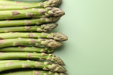 Fresh ripe raw asparagus on green background, closeup. Space for text