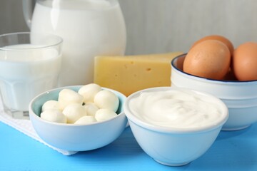 Different dairy products and eggs on light blue wooden table, closeup