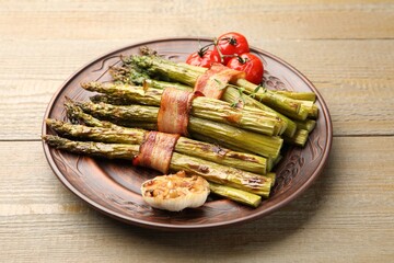 Tasty cooked asparagus served with bacon and spices on wooden table, closeup