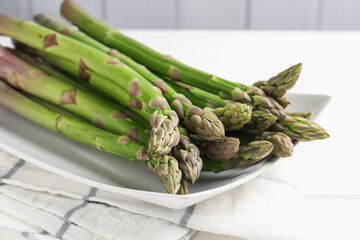 Fresh raw asparagus spears on white wooden table, closeup