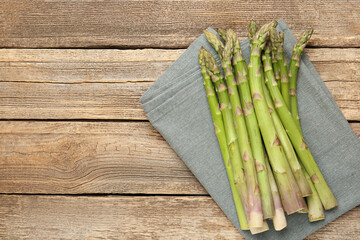 Fresh raw asparagus spears on wooden table, top view. Space for text
