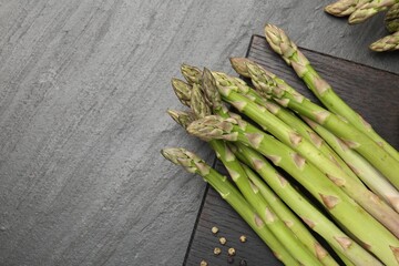 Fresh raw asparagus spears and spices on black table, flat lay. Space for text