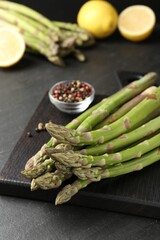 Fresh raw asparagus spears and spices on black table, closeup