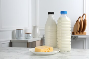 Milk and cheese on white marble table indoors. Dairy products. Space for text