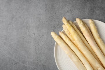 Raw white asparagus spears on grey textured table, top view. Space for text