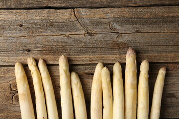 Raw white asparagus spears on wooden table, flat lay. Space for text