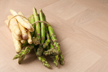 Different raw asparagus spears on wooden table, closeup. Space for text