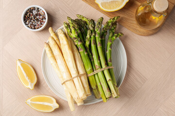 Different raw asparagus spears and spices on wooden table, flat lay