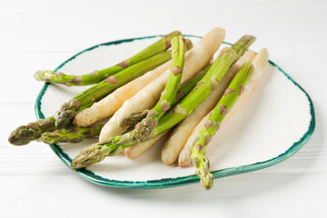 Different raw asparagus spears on white wooden table, closeup