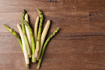 Different raw asparagus spears on wooden table, flat lay. Space for text