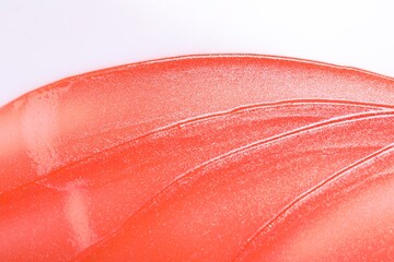 Sample of orange lip gloss on white background, top view