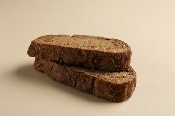 Pieces of fresh rye bread on beige background, closeup
