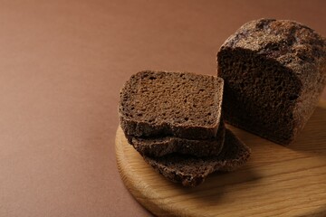 Pieces of fresh rye bread on brown background, closeup. Space for text