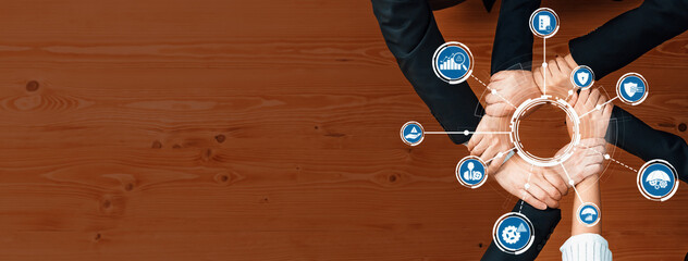 A close-up view of diverse hands joining in collaboration around concept icons, symbolizing teamwork and management strategies on a wooden table. Ideal for business themes. Amity