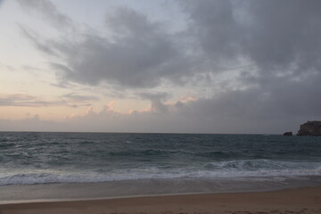 Waves crash onto the shore at Praia do Norte in Nazaré, Portugal, under a cloudy sunset sky—famous for its giant waves and dramatic ocean views.