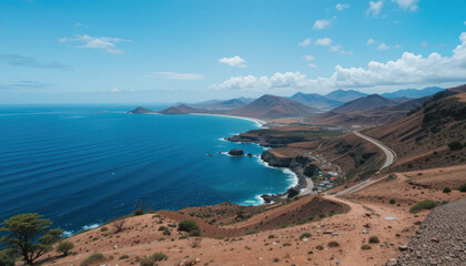 Fototapeta premium Scenic view of a coastline with blue ocean, mountains in the background, and a road winding along the shore.