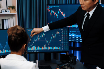 Trading business partners discussing on dynamic stock exchange statistic on pc screens taking note...