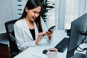 Smiling young Asian businesswoman searching marketing online strategy using smartphone to analyze...