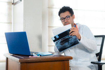 Professional doctor reviews a dental x-ray image and reading medical prescription while working on a laptop in an organized medical office	