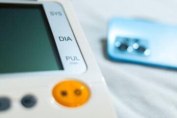 Close up of electronic blood pressure monitor and a modern smartphone placed on a crocheted...