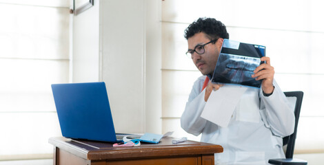 A professional doctor reviews a dental x-ray image and talking to patient through laptop in an organized medical office manifesting telemedicine and technology integration for modern diagnostics.