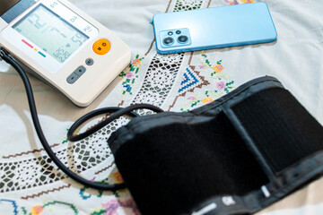 Electronic blood pressure monitor and a modern smartphone placed on a crocheted tablecloth, symbolizing health awareness and technological advancements