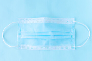 A blue disposable surgical mask placed against a similarly blue background representing medical protection.
