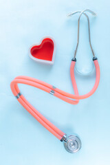 Medical-themed composition featuring a red heart-shaped object next to an orange stethoscope. Perfect for illustrating healthcare, diagnostics, or cardiology-related concepts.
