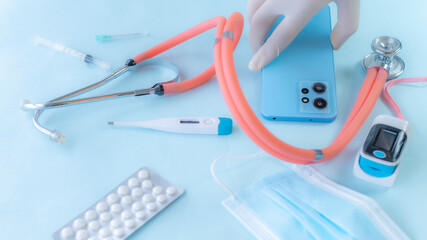 Hand wearing medical glove taking smartphone with some medical tools and accessories.
