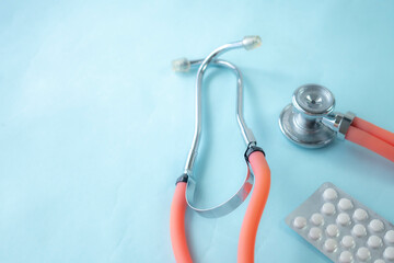 Close up of medical-themed composition featuring stethoscope and medical pills on blue background. Perfect for illustrating healthcare, diagnostics, or cardiology-related concepts.