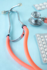 Close up of medical-themed composition featuring stethoscope and medical pills on blue background. Perfect for illustrating healthcare, diagnostics, or cardiology-related concepts.