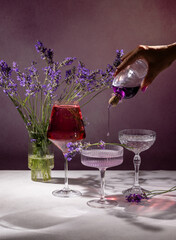 Bartender pouring lavender syrup into cocktail glass with fresh lavender bouquet