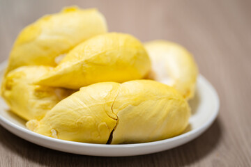 Fresh durian in white plate on wooden table with durian peel. Durian king of fruit. Tropical fruit. 