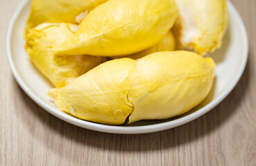Fresh durian in white plate on wooden table with durian peel. Durian king of fruit. Tropical fruit. 