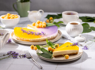 Delicious two colored cheesecake with yellow raspberries and lavender decorating a table