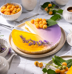 Delicious lavender and yellow raspberry cheesecake being sliced on white plate