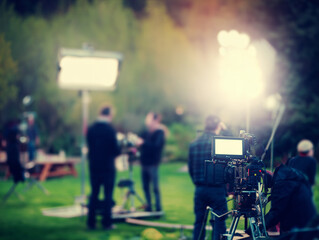 Outdoors film crew capturing scenes with camera gear and lighting effects in a blurry shot