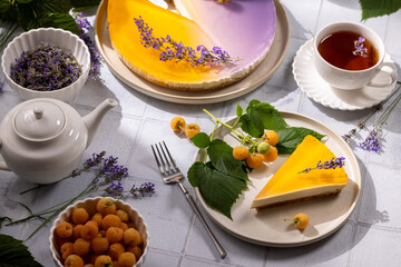 Delicious lavender cheesecake slice served with yellow raspberries and tea