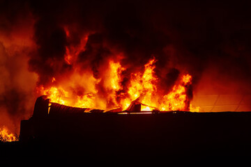 Burning industrial building. Big blaze at night, consequences of attack