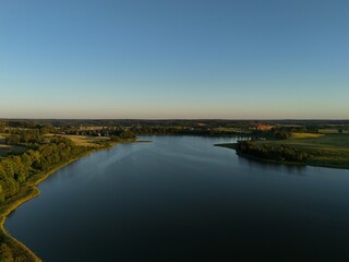 Small lake surrounded by greenery in the evening, aerial view