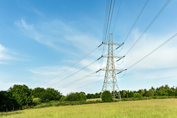High Voltage Pylon and Power Lines in a Grassy Field Against a Blue Sky