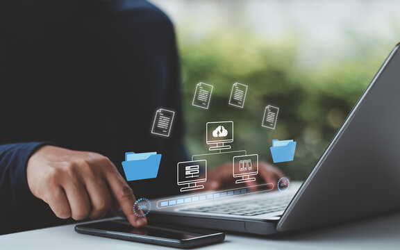 A business professional using a laptop and smartphone to transfer digital files through cloud computing technology. Secure data management, online document file sharing,  upload and download process.