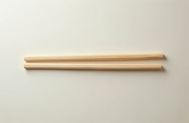 Pair of natural bamboo chopsticks arranged horizontally on clean, light background. Their smooth wooden texture, simple design evoke Asian culinary theme, perfect for food blogs or restaurant menus.