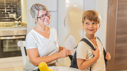 A mother helps her first-grade son pack his backpack for school