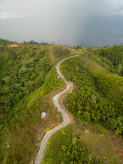 Winding road through forested hills with cloudy sky