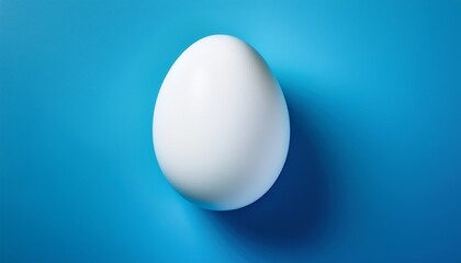 this photograph features a large white egg positioned on a bright blue surface highlighting its smooth texture and rounded shape against the contrasting backdrop