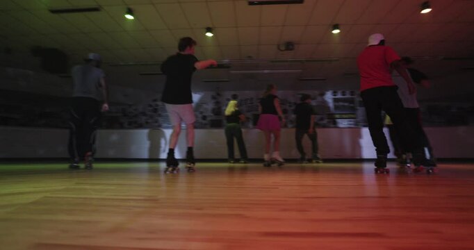 Cinematic swooping shot around amazing group of professional skaters dancing on floor with colorful lights
