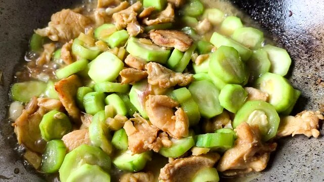 Frying  chicken breast with angled squash in pan, indoor Chiangmai Thailand.