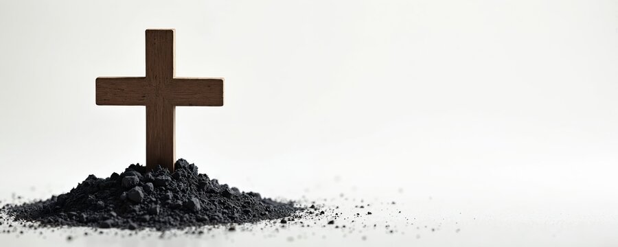 Wooden cross on pile of ashes signifies Ash Wednesday, Lent, religious repentance. Solemn symbol represents mortality, humbleness, spiritual renewal for Christian traditions during holy observance.