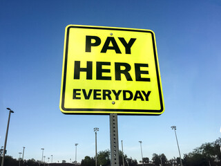A yellow sign stating Pay Here Everyday